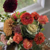 Mixed bouquet of orange, pink, and burgundy flowers in a vase