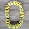Yellow and pale green flower garland arranged in an oval on a wood surface