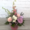 Pink and white roses with purple blooms in a pink vase