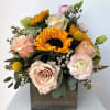 Mixed bouquet with sunflowers, roses, and pale pink blooms in a wooden box
