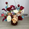 This arrangement has a romantic, artistic feel with rich burgundy blooms, creamy
