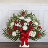 Standing floral spray with red roses and white daisies on a white easel