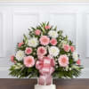 Pink and white floral arrangement with a pink ribbon bow in a white container