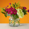 Mixed bouquet of pink and yellow flowers in a clear glass vase