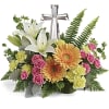Floral arrangement with white lilies, pink roses, and orange gerbera daisies topped by a silver cross