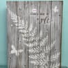 Rustic gray wooden sign with white foliage, butterflies, and the words "Every day is a gift".