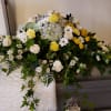 Large white and yellow funeral spray with roses, daisies, and hydrangea