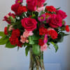 Bouquet of hot pink roses and red carnations in a clear glass vase