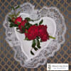 Red roses arranged in a white heart-shaped holder with lace trim