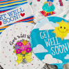 Four round get-well balloons with colorful printed designs