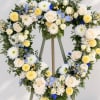 Heart-shaped floral wreath with white, yellow, and blue flowers on an easel