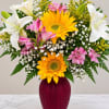 Bouquet of sunflowers, lilies, and pink alstroemeria in a burgundy vase