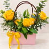 Yellow roses arranged in a pink gift bag with a ribbon bow