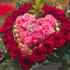 Heart-shaped rose arrangement with pink and red roses and chocolates