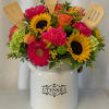 Bright mixed flower arrangement in a white utensil jar with wooden kitchen tools