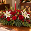 Red roses and white lilies arranged around a red taper candle