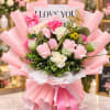 Pink and white rose bouquet wrapped in pink paper with a "I LOVE YOU" card
