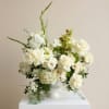 White floral arrangement in a white vase with tall green stems