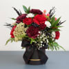 Red and white floral arrangement in a black hatbox with a ribbon
