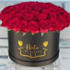 Red roses arranged in a black round box with gold lettering