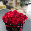 Red roses arranged in a black hat box with a red ribbon