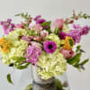 Mixed bouquet of pink, yellow, and green flowers in a textured vase