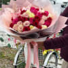 Large bouquet of pink, red, and cream roses wrapped in pastel paper