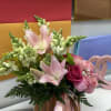 Pink lilies and roses arranged in a wicker basket with ribbon