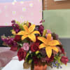 Mixed bouquet with orange lilies and red roses in an orange vase