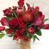 Red floral bouquet with roses, tulips, and calla lilies in a burlap-wrapped vase
