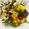 Mixed bouquet with yellow roses, calla lilies, and purple flowers in a green vase