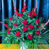 Large arrangement of red roses with tropical greenery in a white vase