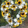 A bright funeral open heart with sunflowers, daisies and carnations on a