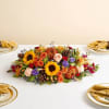 Low centerpiece with sunflowers, roses, and autumn flowers on a table