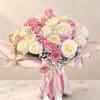 Bouquet of pink and cream roses wrapped in pink paper with ribbon