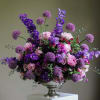 Large purple and pink floral arrangement in a silver pedestal vase