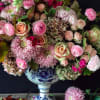Pink and cream floral arrangement in a blue-and-white pedestal vase