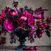Deep pink and burgundy floral arrangement in a black pedestal vase