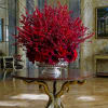 Large red floral centerpiece in a silver urn on a round table