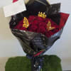 Bouquet of red roses wrapped in black paper with a small crown topper