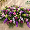 Large mixed floral arrangement with roses, lilies, and purple blooms