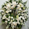 Large white floral wreath on a wooden stand