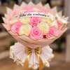 Pink and cream rose bouquet wrapped in pale pink paper with a gold ribbon