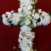 White floral cross on a stand against a red background