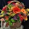 Basket arrangement with orange, red, and purple flowers