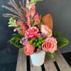 Pink roses and snapdragons arranged in a white vase