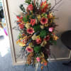 Tall mixed floral spray with pink and orange blooms on a stand