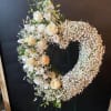 White floral wreath on a stand with roses and baby's breath