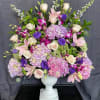 Large pastel floral arrangement in a white pedestal vase
