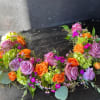 Colorful floral wreath with roses, hydrangeas, and small purple blooms